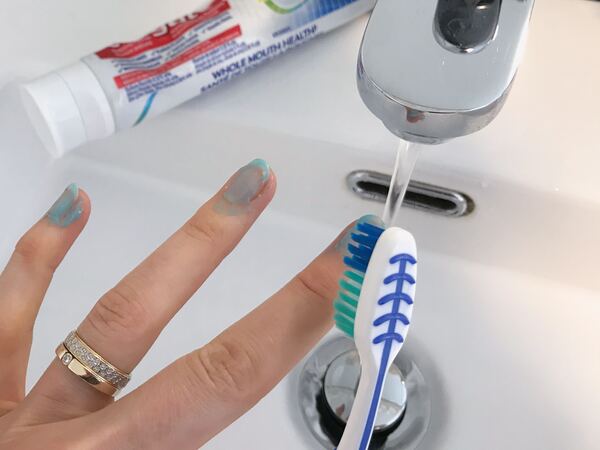 Dùng bàn chải để chải đều kem đánh răng lên móng tay của bạn (Nguồn: Internet)
